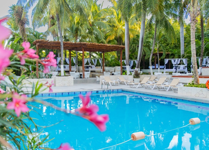 Pool among tropical flowers with cabanas and loungers at Oh! Cancun