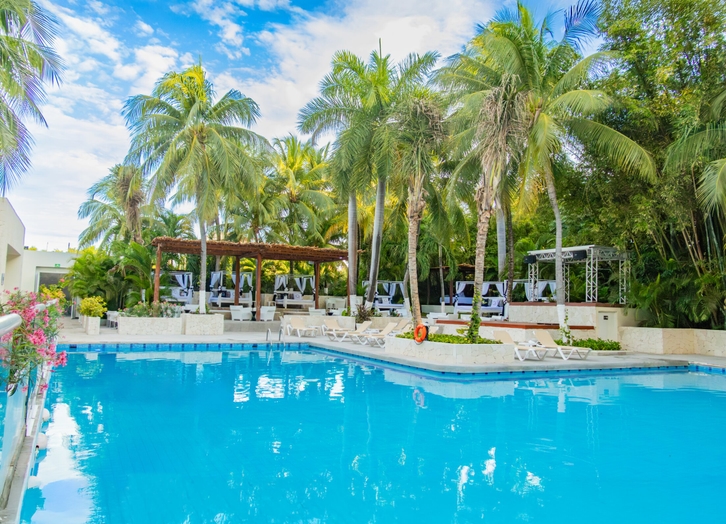 Main pool with Balinese daybeds under the pergola and palm trees at Oh! Cancun
